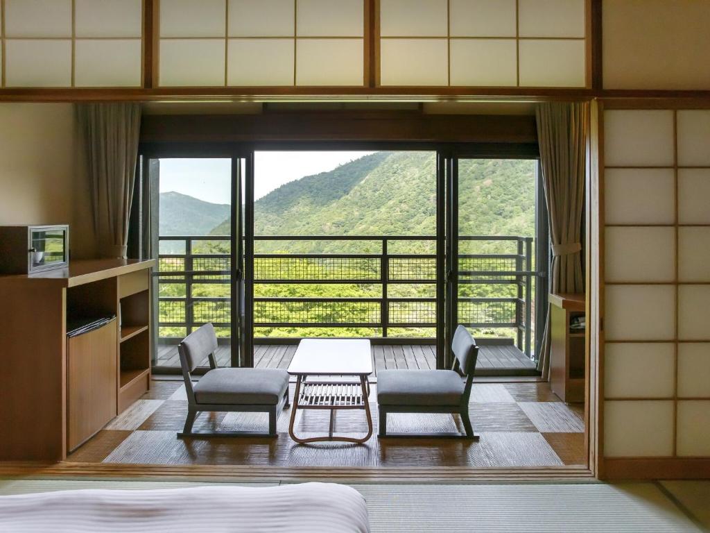 una camera da letto con tavolo, sedie e una grande finestra di Hakone Kowakien Mikawaya Ryokan a Hakone