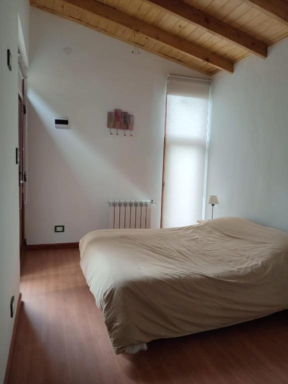 a white bedroom with a large bed and a window at Casa Maitén in El Bolsón