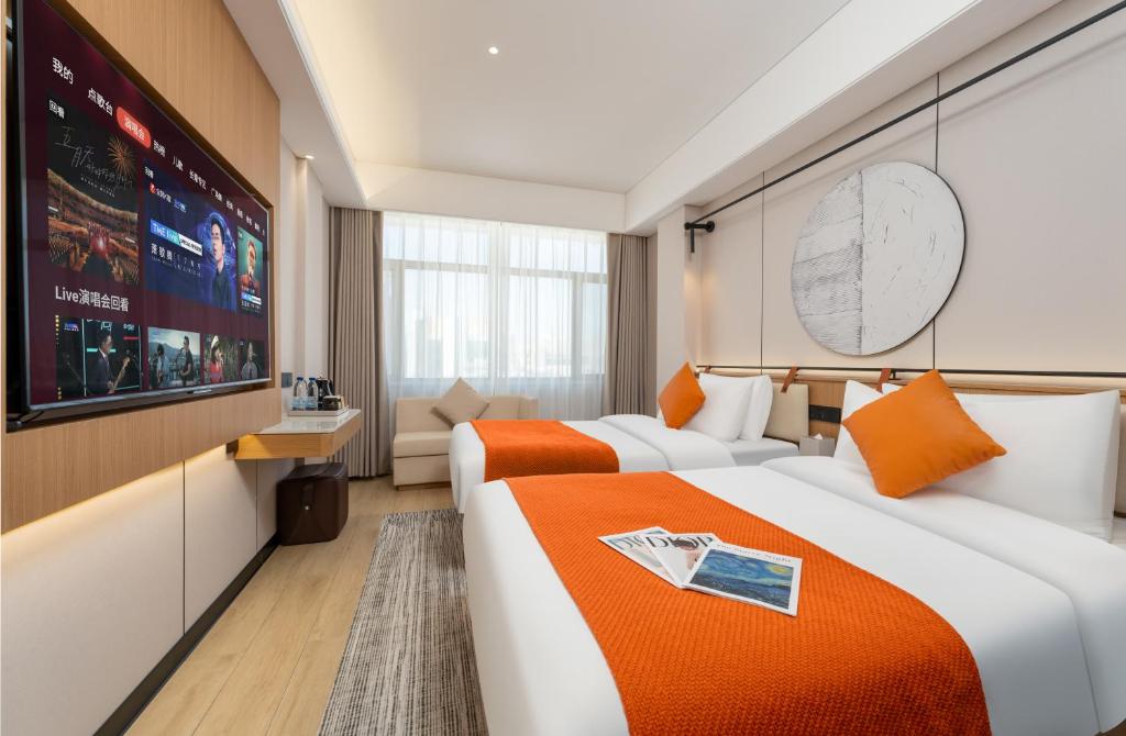 two beds in a hotel room with a large screen at Jiuquan Smart Hotel in Jiuquan
