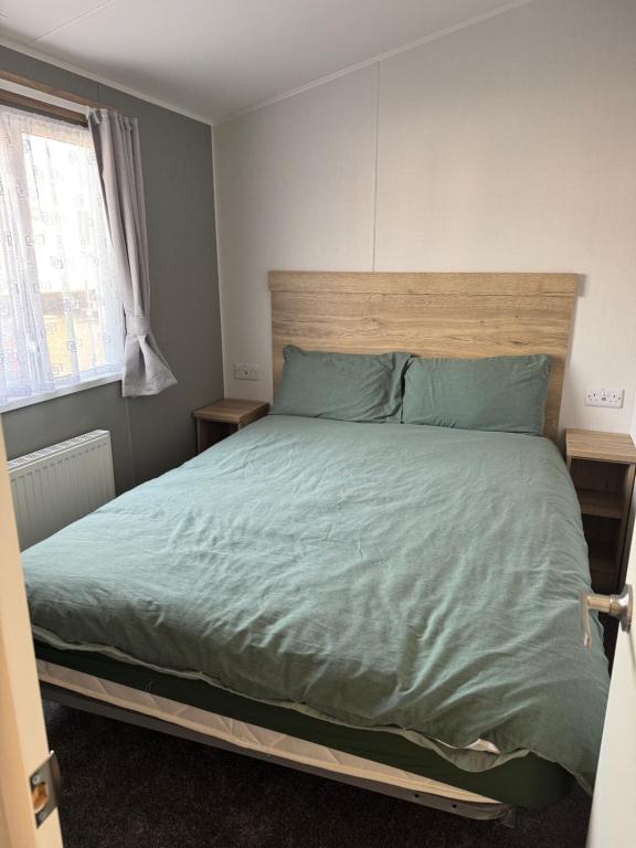 a bedroom with a bed with green sheets and a window at 30, Sunset Terrace in Lytchett Minster