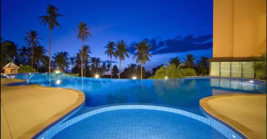 a swimming pool at night with palm trees at Avanta in Ban Mae Nam