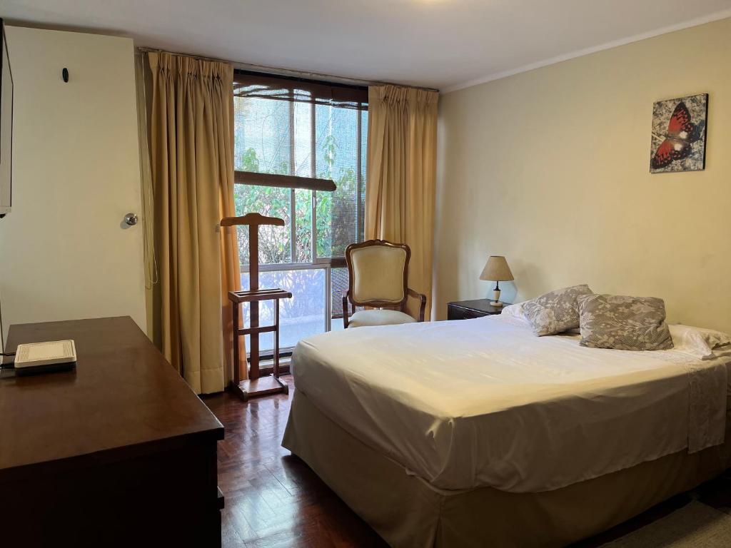 a bedroom with a bed and a desk and a window at HOMESTAY Yas & Jay in Lima