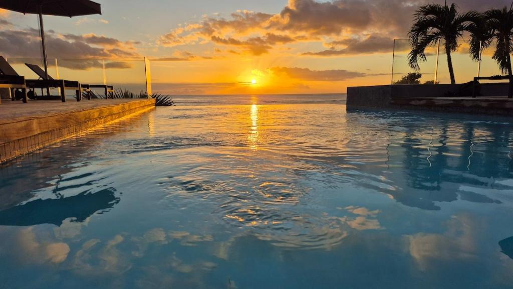 a sunset over a swimming pool on a beach at Beachfront Chic Penthouse in Rivière Noire