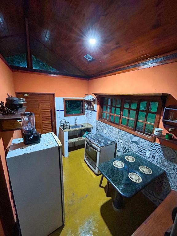 a kitchen with a refrigerator and a table in it at Chalé Bangalo in Bocaina de Minas