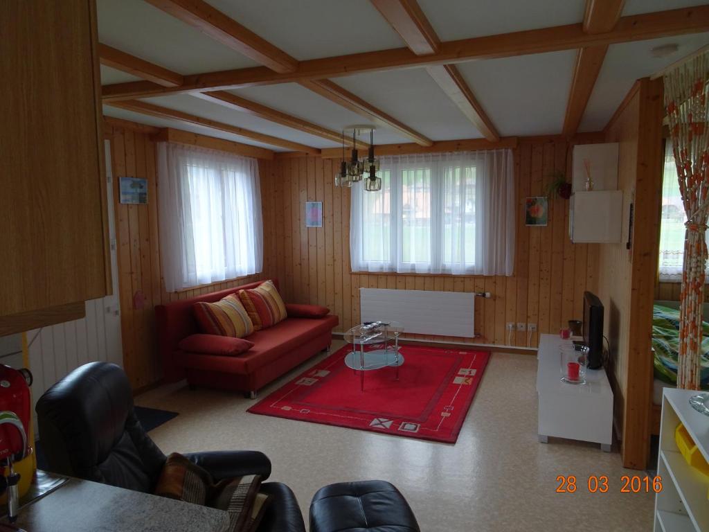 un soggiorno con divano rosso e tappeto rosso di Neumühleweg 19 a Lauperswil