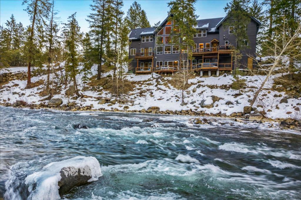 a large house in the snow next to a river at White Water Lodge in Leavenworth