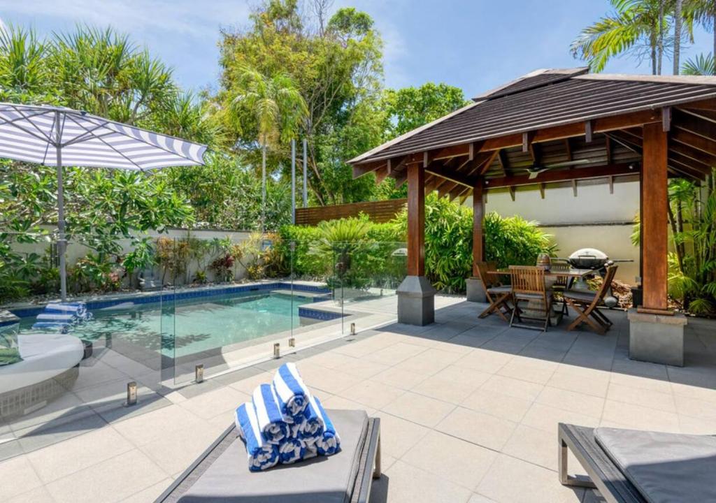 un patio trasero con piscina y pabellón en Tali Beach House Retreat, en Oak Beach