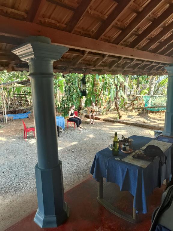 a table under a pavilion with people sitting in the background at Perch Next door in Kannur