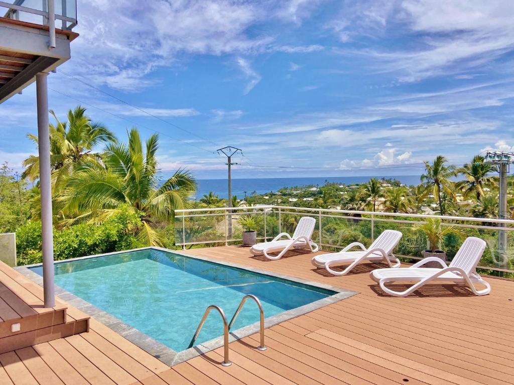 una terraza con piscina, sillas y el océano en Villa Cormorans, en Saint-Gilles-les-Bains
