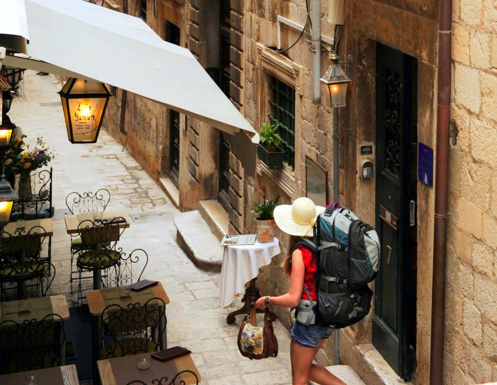 Una mujer con una mochila mirando fuera de un edificio en Old Town Hostel, en Dubrovnik
