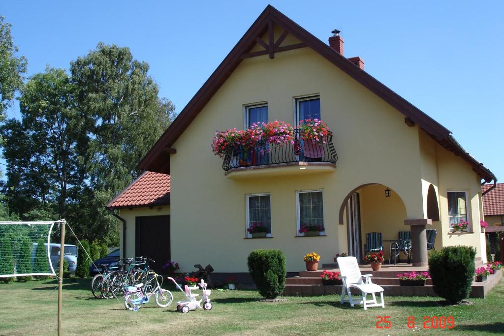 una casa con flores en un balcón con bicicletas en el patio en Pokoje Gościnne u Elżbiety, en Sztutowo