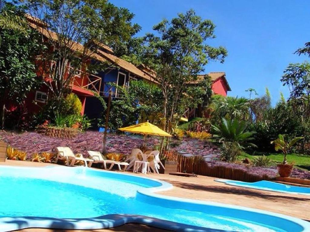 una piscina con sillas, una sombrilla y una casa en Mirante de Lençóis en Lençóis