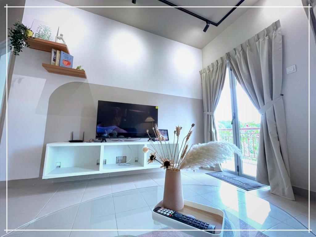 - un salon avec une télévision et un vase fleuri dans l'établissement Tiara Desaru Residence by UCome Homestay, à Bandar Penawar