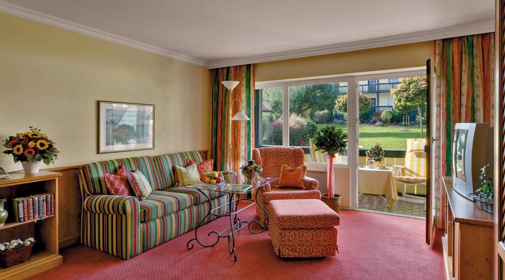 a living room with a couch and chairs and a television at Hotel Birnbacher Hof in Bad Birnbach