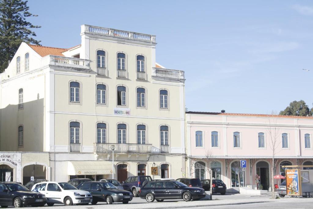 un gran edificio blanco con coches estacionados frente a él en Hostel 402, en Figueira da Foz