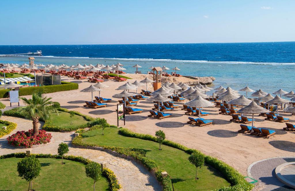 a beach with umbrellas and chairs and the ocean at Charmillion Sea Life Resort in Sharm El Sheikh