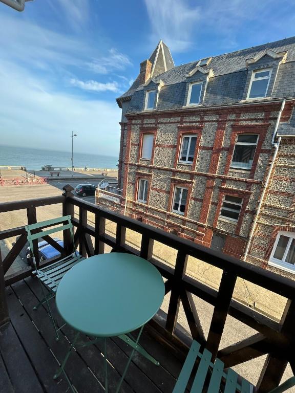 une table bleue sur un balcon avec un bâtiment dans l'établissement La danse des vagues, vue mer, à Fécamp