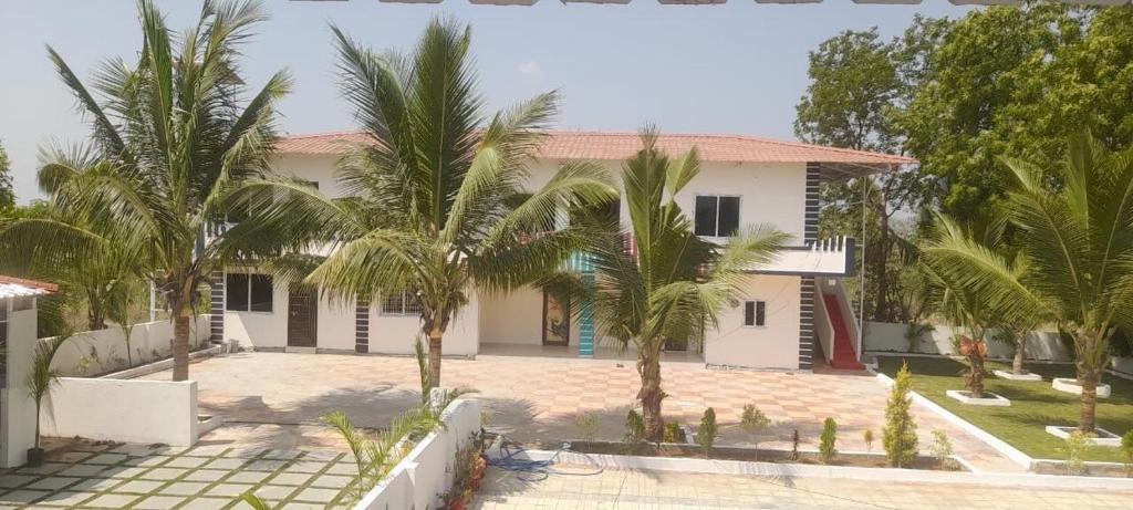 DhundgolにあるAkshay Farmsの前にヤシの木がある家