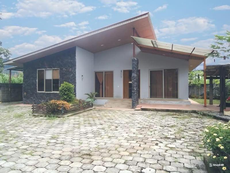 ein kleines weißes Haus mit einer Steinzufahrt in der Unterkunft Carachula Guesthouse in Macas