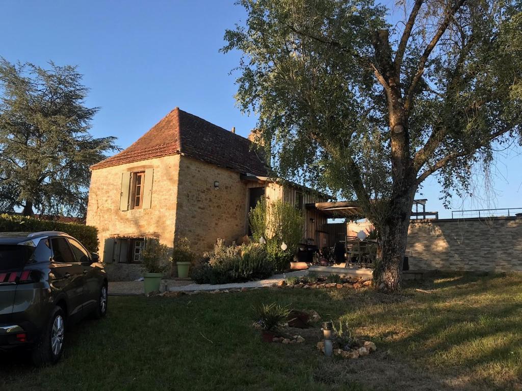une maison avec une voiture garée devant dans l'établissement Maison typique Périgourdine avec piscine, à Saint-Martial-de-Nabirat