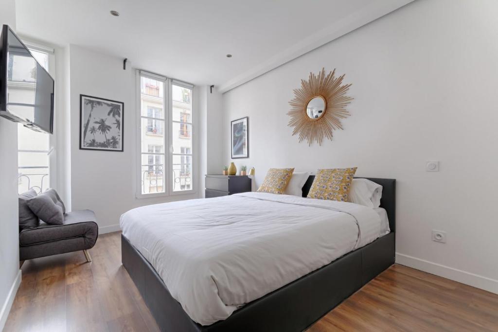 une chambre avec un grand lit avec un miroir au mur dans l'établissement TBS 310 - Elegant studio near Marais district, à Paris