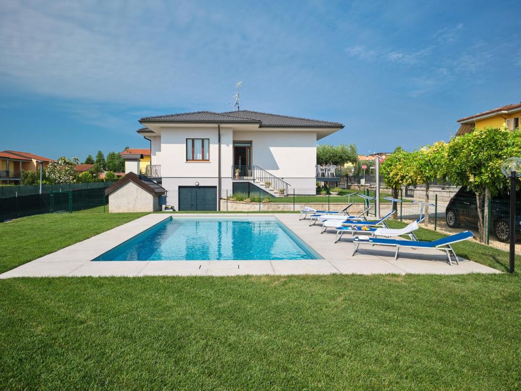 une piscine avec des chaises longues et une maison dans l'établissement VILLA HARMONY - Regarda Travel, à Lazise