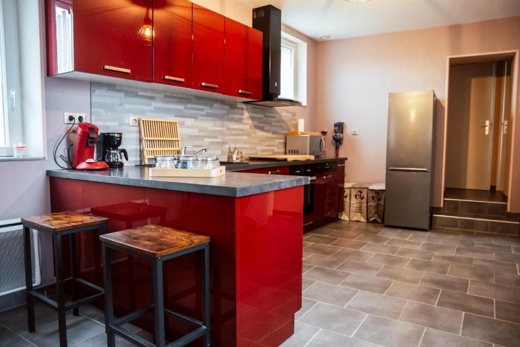 a kitchen with red cabinets and a stainless steel refrigerator at le refuge des cépages - essoyes in Essoyes