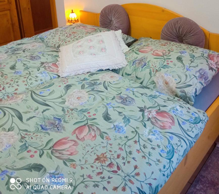 a bed with a floral bedspread and a pillow on it at Pension Fanlor in Zubčická Lhotka