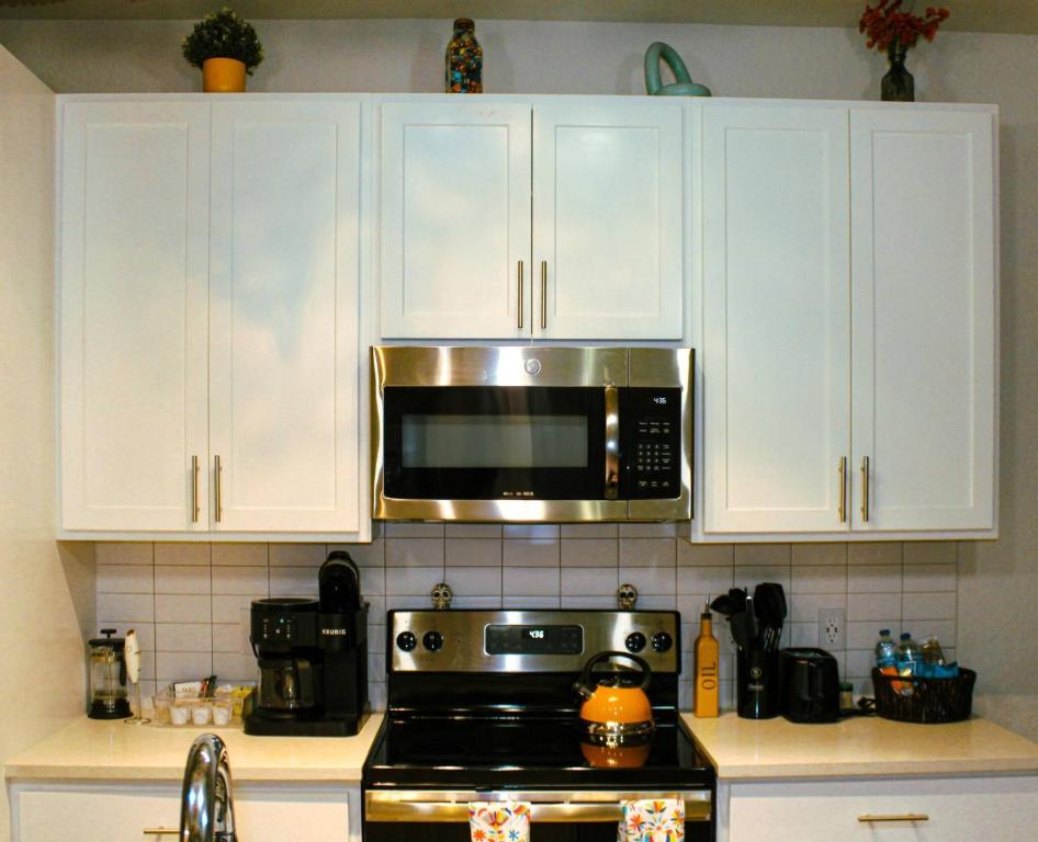 - une cuisine avec des placards blancs et un four micro-ondes au-dessus d'une cuisinière dans l'établissement IG-Worthy Fiesta DT Retreat hotel Apt with free Parking and Pets Allowed, à San Antonio