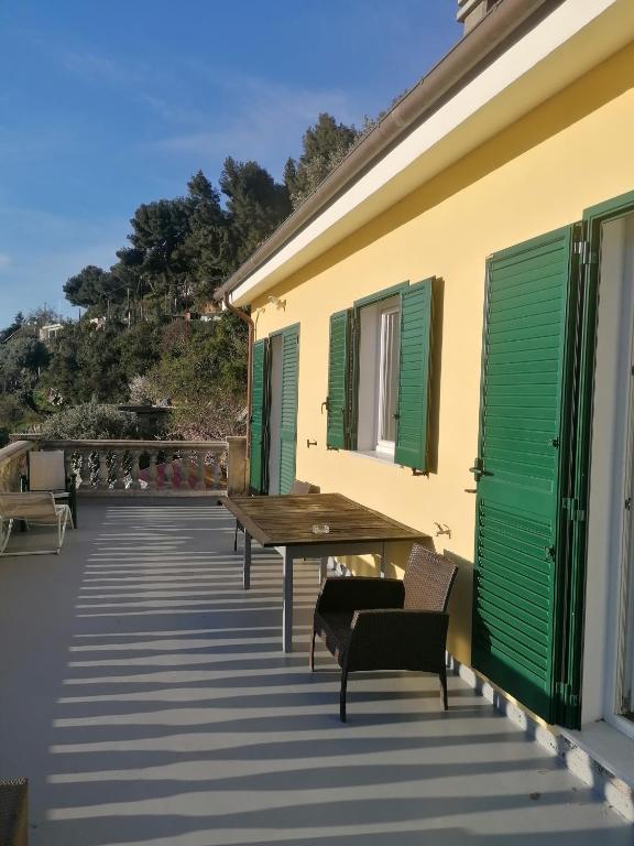 une terrasse avec volets verts, table et chaises en bois dans l'établissement Monaco' hills appartement, à Roquebrune-Cap-Martin