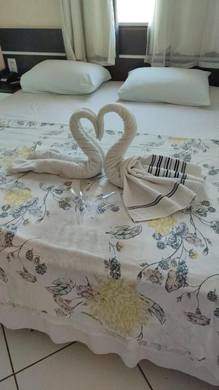 two swans are sitting on a bed with towels at Hotel União in Pojuca