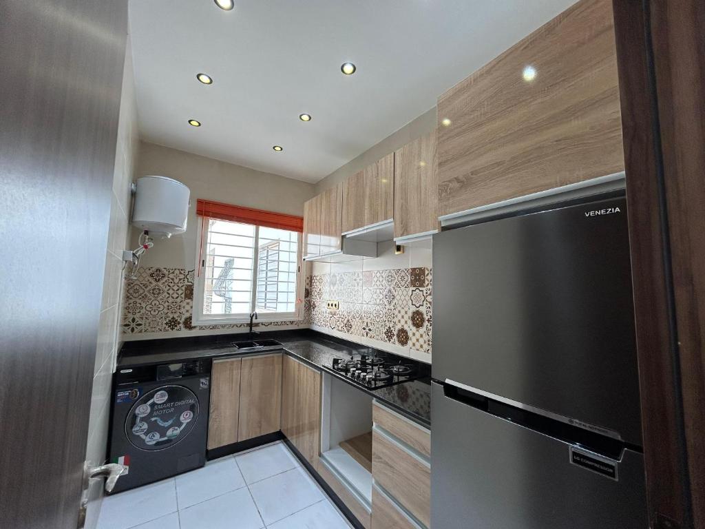 a kitchen with wooden cabinets and a stainless steel refrigerator at Sable d'or in Tangier