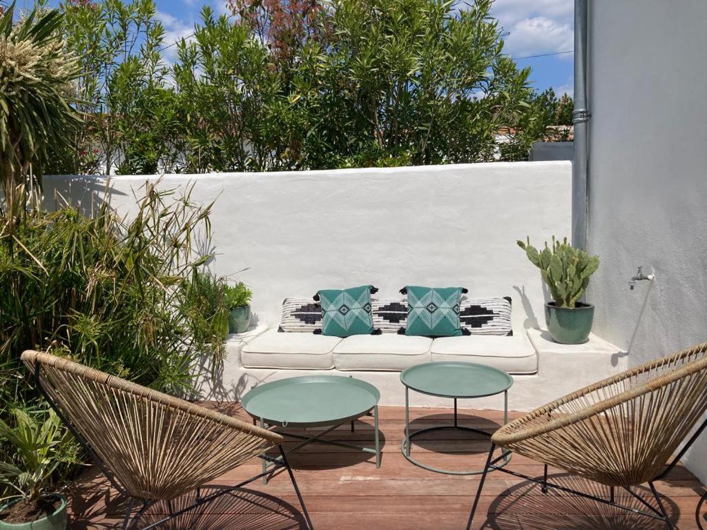 d'une terrasse avec deux chaises et un canapé avec des oreillers bleus. dans l'établissement Charmante maison Charentaise, à Breuillet