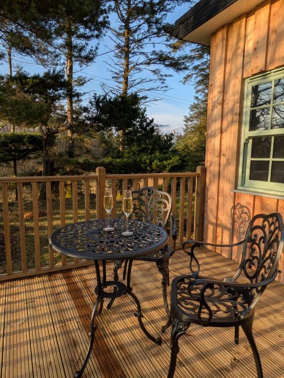 a table and two chairs on a deck with wine glasses at Tullochard House B&B in Dunvegan