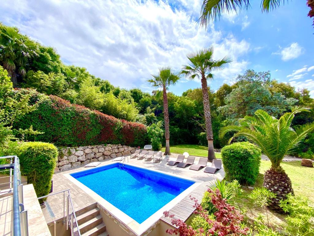 une piscine dans un jardin avec des chaises et des arbres dans l'établissement Villa Bamboo Zen, à Cannes