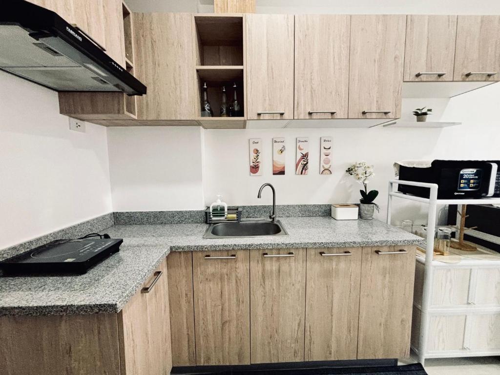 a kitchen with wooden cabinets and a sink at Bright Airy Urban Escape in Iloilo City
