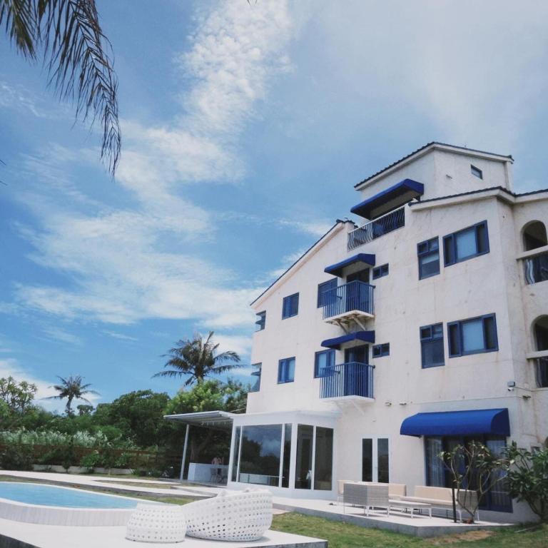 a large white building with a pool in front of it at ChuLe Villa x Maobitou in Hengchun South Gate