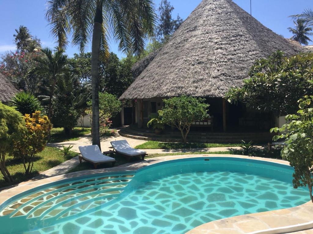 un complejo con piscina y techo de paja en Villa Morosa, en Watamu