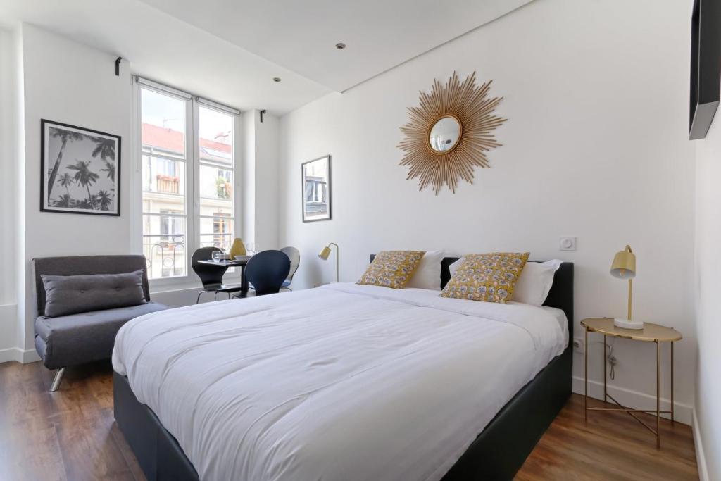une chambre blanche avec un grand lit et une chaise dans l'établissement TBS 313 - Elegant studio near Marais district, à Paris