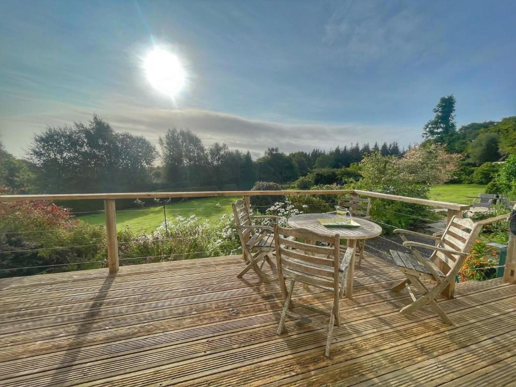 a wooden deck with a table and chairs on it at Cherryford House in Gidleigh