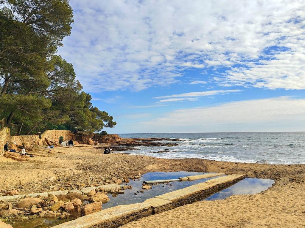 une plage avec des personnes assises sur le sable et l'eau dans l'établissement Très beau T2 à côte de la plage, à Saint-Raphaël