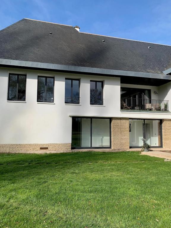 une grande maison blanche avec une cour gazonnée dans l'établissement Appartement Le Domaine De Louis, à Croisy-sur-Eure