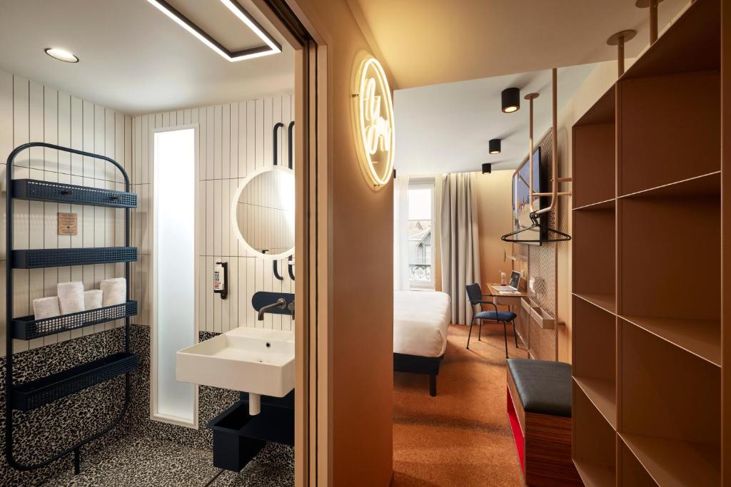 a hotel room with a bathroom with a bed and a sink at YOU Are Deauville in Deauville