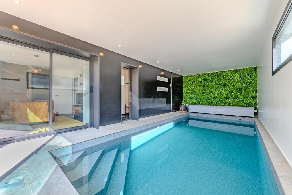 a swimming pool in a house with a green wall at la villa iodée, le confort d une maison neuve équipée d une piscine intérieure chauffée toute l année, très proche des plus belles plages in Fouesnant