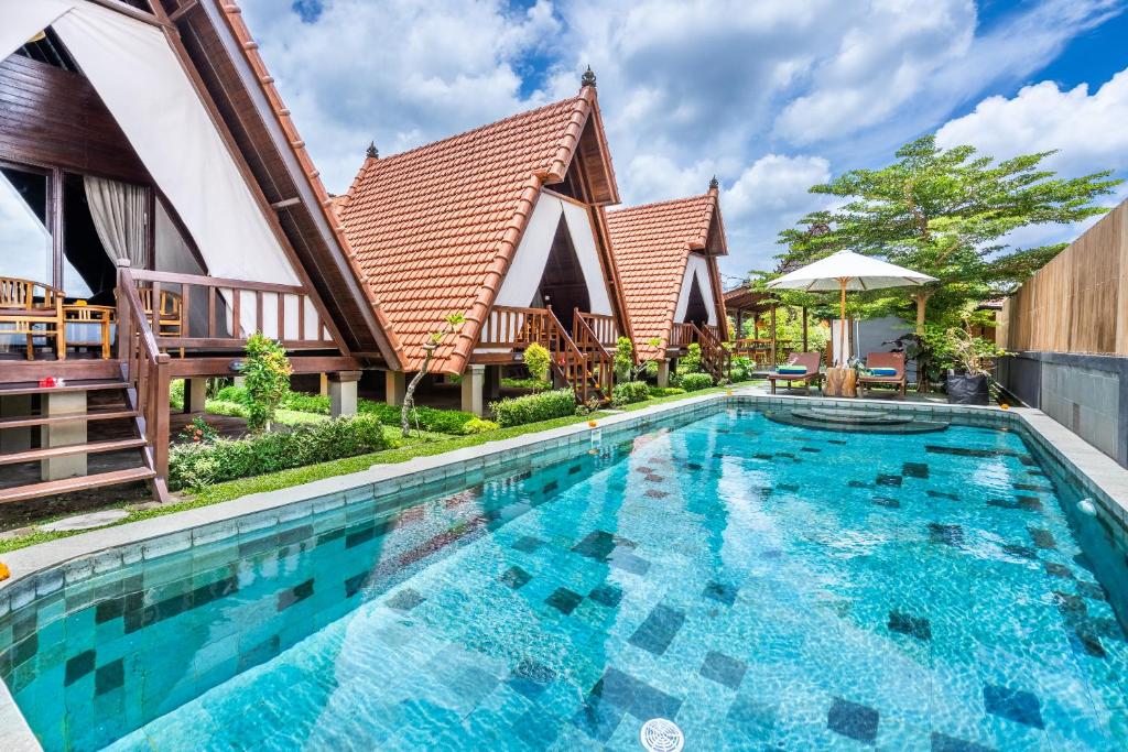 a large swimming pool in front of a house at Lumbung Sari villa ubud in Ubud