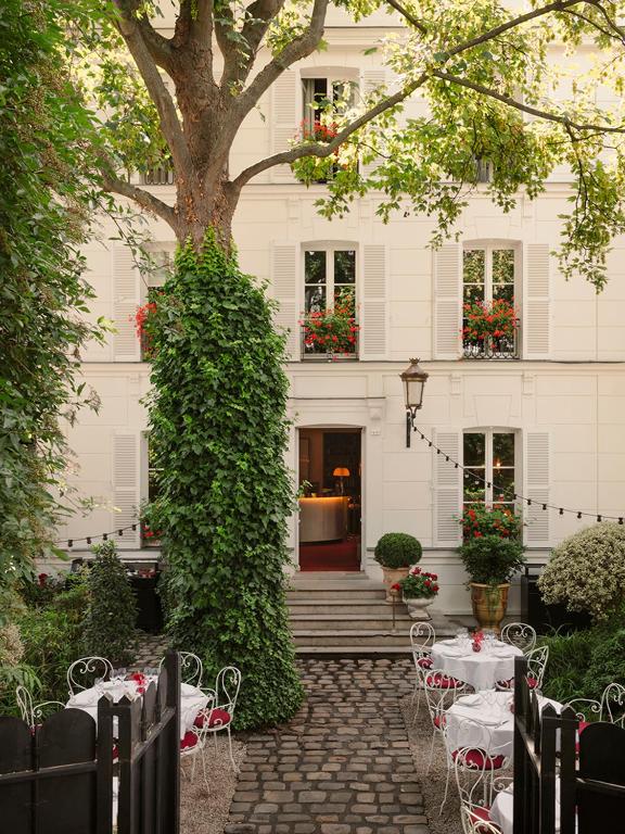 une table et des chaises devant un bâtiment dans l'établissement Hôtel Particulier Montmartre, à Paris