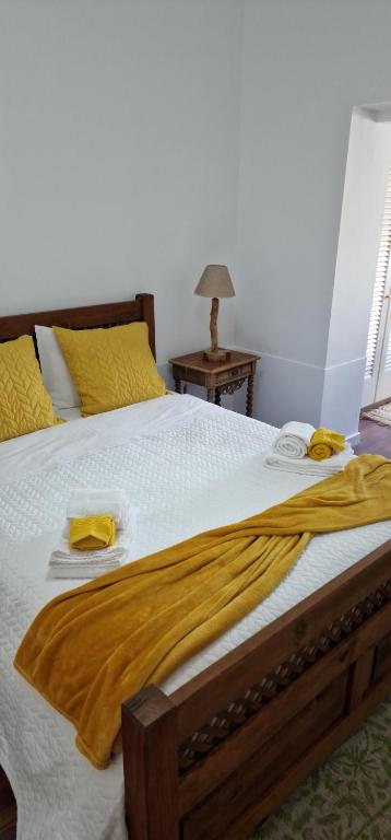a large bed with yellow sheets and towels on it at Casa do Bairro - O seu refúgio in Ponta Delgada
