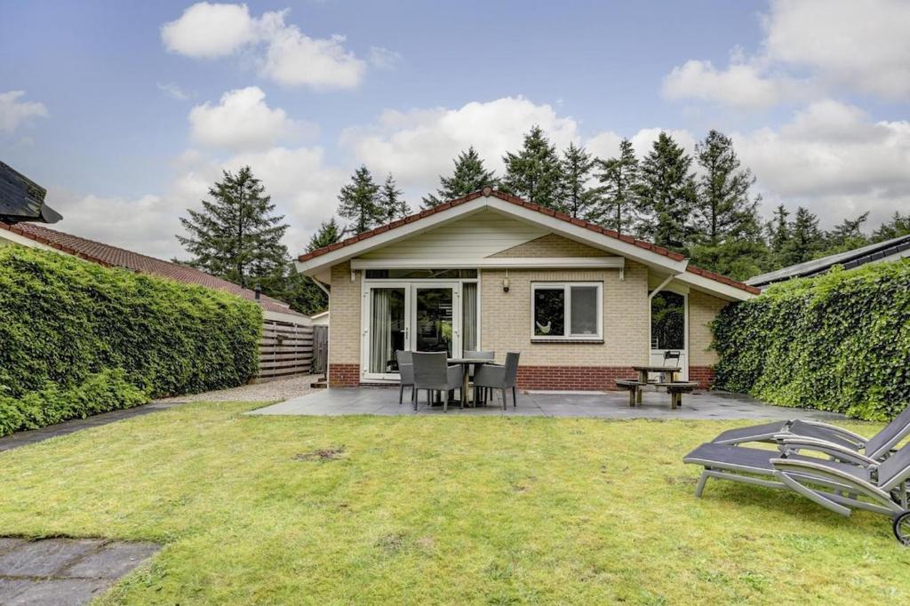 a house with a patio with a table and chairs at Luxe boshuisje op kleinschalig park op de Veluwe in Putten