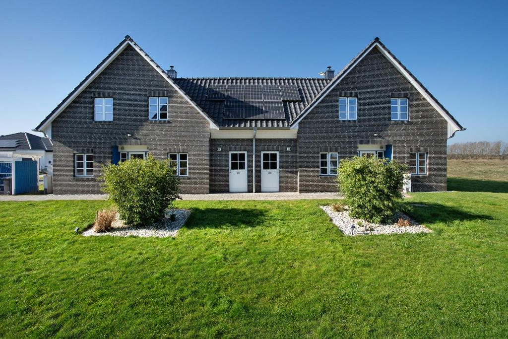 KrumminKomfortables Ferienhaus Allee的一座大砖房,在院子里有两丛灌木