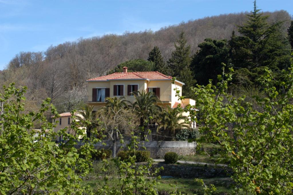 a house on a hill with trees in the foreground at Valle Maira, Agriturismo nel Parco dei Nebrodi in Tortorici